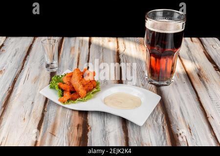 Piatto con ali di pollo con salsa rossa accompagnata da un birra scura Foto Stock