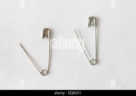 due perni di sicurezza in argento aperti su sfondo bianco Foto Stock
