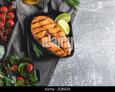 bistecca di salmone di pesce alla griglia, trota in una padella alla griglia, piccante, pomodoro, primo piano, vista dall'alto Foto Stock