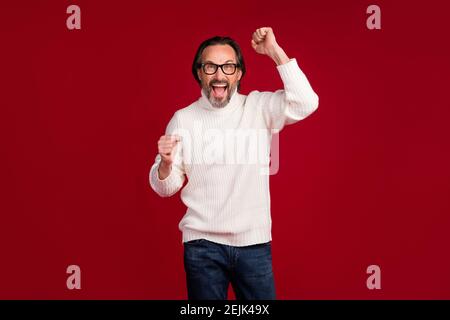 Ritratto fotografico di un vecchio uomo d'affari allegro che indossa un look elegante sorridente gesturing come vincitore pazzo isolato su sfondo di colore rosso. Foto Stock