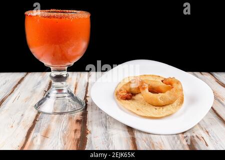 Piatto con un taco gamberi accompagnato da un grande bicchiere di birra ghiacciata con sale e limone Foto Stock