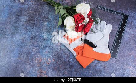 Concetto del giorno del padre con baffi, rose bianche, rosse, guanti e strumento ad angolo retto su sfondo blu. Spazio per il testo. Foto Stock