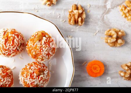 Una disposizione piatta di bancone della cucina con una piastra piatta in porcellana. Palline di beatitudine di carote fresche fatte in casa (miscela di crumbles di biscotti, noce e purea di carote) Foto Stock