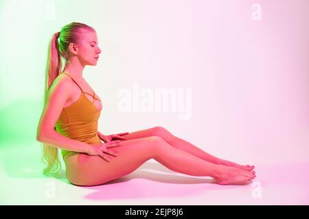 Ginnastica femminile stanca seduta sul pavimento in studio Foto Stock