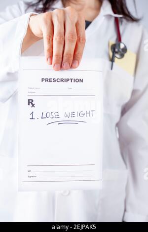 Una donna caucasica in camice bianco sta prescrivendo perdita di peso a un paziente obeso o sovrappeso nel suo ufficio. Un'immagine concettuale per lo stile di vita m Foto Stock