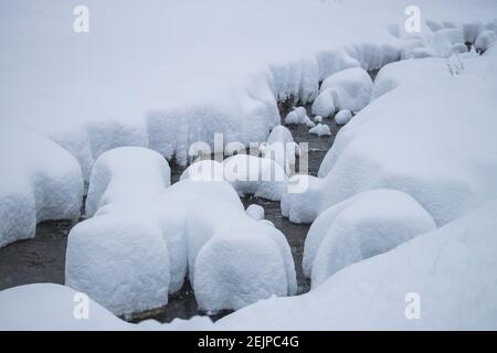 rocce nel mezzo di un ruscello coperto da un molta neve Foto Stock