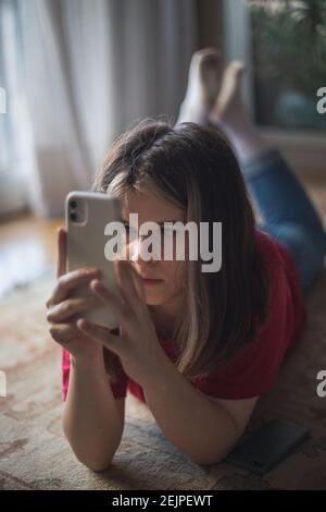Una ragazza adolescente guarda lo schermo del suo smartphone Foto Stock