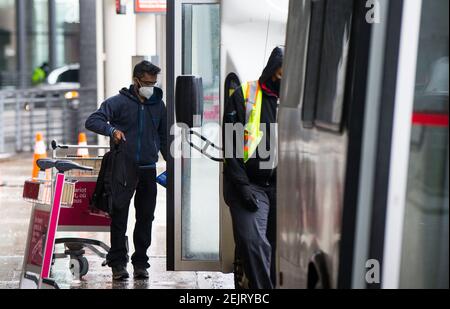 Mississauga, Canada. 22 Feb 2021. Un viaggiatore che indossa una maschera facciale prende un autobus navetta per un hotel designato dal governo all'Aeroporto Internazionale di Toronto a Mississauga, Ontario, Canada, il 22 febbraio 2021. A partire da Lunedi', i viaggiatori che arrivano in Canada in aereo sono tenuti a fare un test molecolare COVID-19 prima di uscire dall'aeroporto. Gli ospiti sono inoltre tenuti a mettere in quarantena per tre giorni in un hotel designato dal governo a proprie spese fino a quando non ottengono un risultato. Credit: Zou Zheng/Xinhua/Alamy Live News Foto Stock