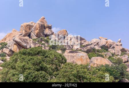 Chitradurga, Karnataka, India - 10 novembre 2013: Fort o Elusuttina Kote. Un mucchio di mazzi come parte delle difese sotto il cielo blu con fogliame verde Foto Stock