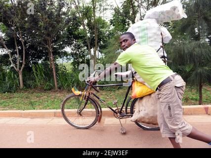 Un uomo ruandese che spinge la sua bicicletta caricata nella rurale Ruanda. Foto Stock