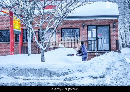 Milford, Stati Uniti. 22 Feb 2021. Un uomo libera una passerella innevata di fronte a una casa a Milford, Pennsylvania. Ancora un'altra tempesta si è abbattuta su un nordest stanco di neve, scendendo fino a sei pollici in alcune aree, compresa la Pennsylvania orientale. Credit: SOPA Images Limited/Alamy Live News Foto Stock
