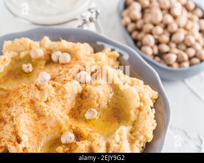 In casa hummus con olio d'oliva nella ciotola grigio e tahini. Tradizionali del medio oriente antipasti fatti in casa hummus - vegano sani snack di pasta. Dieta vegetariana e nutrizione alimento proteico concetto e idea Foto Stock