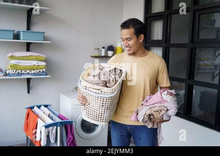 Housewwork. asian Man facendo lavanderia a casa caricando i vestiti in lavatrice Foto Stock