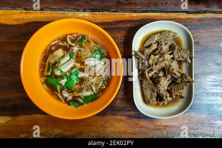 Vermicelli di riso con carne d'anatra stufata (noodle d'anatra) e cottura dell'ala d'anatra bollita in salsa di soia su tavolo di legno. Messa a fuoco selettiva. Foto Stock