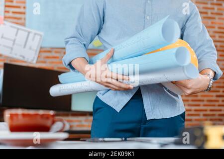 ingegnere tenere ingegnere disegno progetti di progettazione e casco di sicurezza in sala nella costruzione del sito. Foto Stock