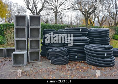 Cassoni scatolari quadrati in cemento armato e rotoli di corrugati neri tubi di scarico flessibili in un cantiere a nord-est Italia Foto Stock