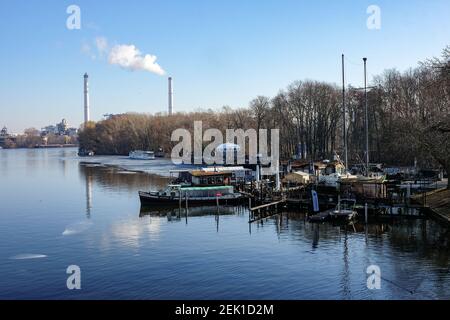 Berlino, Germania. 22 Feb 2021. Vista dal Ponte di Abtei nel Parco di Treptower delle barche sulle rive dello Sprea a Plänterwald e la centrale di Klingenberg combinata calore ed energia in tempo di sole. La casa rotonda in plastica UFO chiamata 'futuro' è stata progettata dall'architetto finlandese Matti Suuronen. Credit: Jens Kalaene/dpa-Zentralbild/ZB/dpa/Alamy Live News Foto Stock