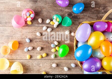 Immagine piatta delle uova di pasqua in plastica che vengono riempite con cioccolatini prima della caccia all'uovo di pasqua. È un'attività divertente per i bambini che cercano uova e g Foto Stock