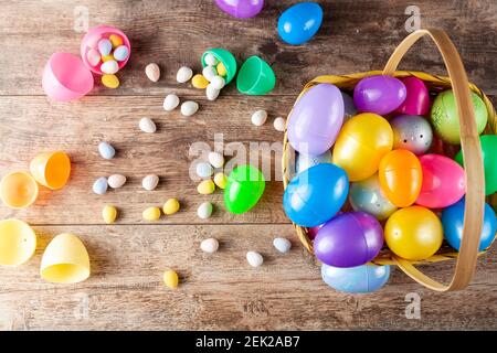 Immagine piatta delle uova di pasqua in plastica che vengono riempite con cioccolatini prima della caccia all'uovo di pasqua. È un'attività divertente per i bambini che cercano uova e g Foto Stock