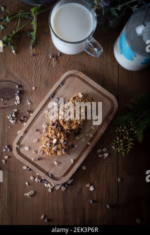 Biscotti al cioccolato con scaglie di farina d'avena e bicchiere di latte. Biscotti sani su sfondo naturale di legno. Foto Stock