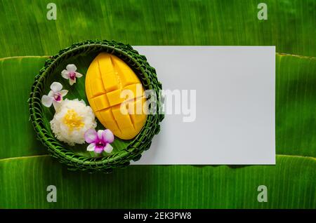 Dessert tailandese - riso adesivo mango su piatto di foglia di banana mette su carta bianca bianca e sfondo foglia di banana. Foto Stock