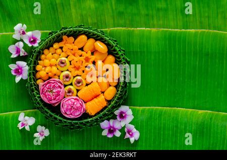 I dessert di nozze thailandesi su piatto di foglie di banana o krathong decorano con fiore di loto per la cerimonia tradizionale tailandese su sfondo foglia di banana. Foto Stock