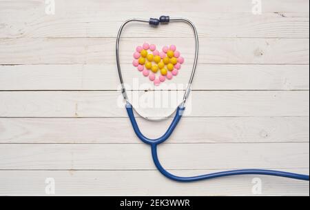 Raschiando sul tavolo e cuore da pillole legno sfondo vitamine di salute di tessitura Foto Stock