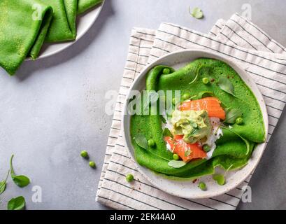 pancake, crepes con spinaci, salmone e avocado in piastra di ceramica Foto Stock