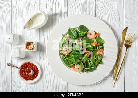 Insalata di micrograni con gamberi all'avocado, foglie di spinaci, germogli di girasole freschi, yogurt e condimento di tahini con fiocchi di peperoncino serviti su un whit Foto Stock