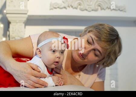 La nonna guarda la bambina con amore. Una donna anziana e una ragazza di tre mesi. Foto Stock