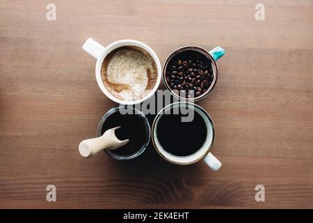 Più tazze di caffè, latte, fagioli e caffè macinato in vaso su sfondo di legno. Foto di alta qualità Foto Stock