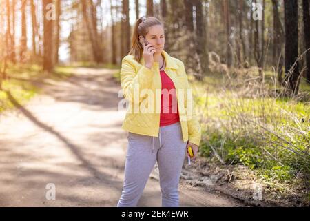 donna sta parlando emotivamente al telefono nella foresta . concetto di comunicazione cellulare 5g Foto Stock