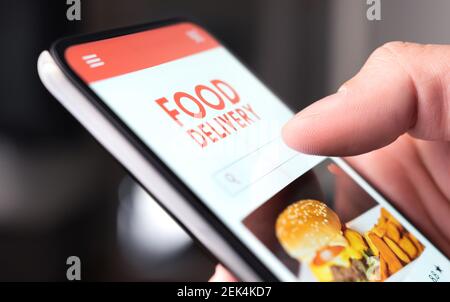 Servizio di consegna cibo al ristorante al telefono. Menu "Take away" nell'app mobile digitale. Uomo che ordina pizza da asporto o hamburger online. Pranzo veloce consegnato. Foto Stock