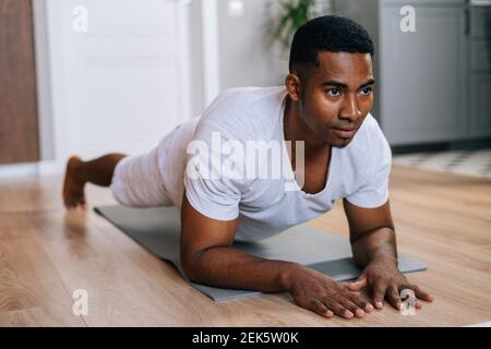 Vista ravvicinata dell'uomo afroamericano che si esercita in posizione a tavola sul pavimento durante l'allenamento. Foto Stock