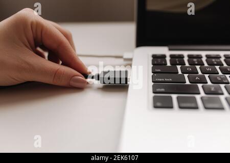 Mano femminile che inserisce l'unità flash USB nera nel computer portatile Foto Stock