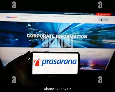 Persona titolare smartphone con logo della società di trasporto Prasarana Malaysia Berhad sullo schermo di fronte al sito web. Mettere a fuoco il display del telefono. Foto Stock