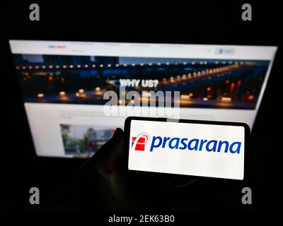 Persona che tiene il telefono cellulare con il logo aziendale del fornitore di trasporti Prasarana Malaysia Berhad sullo schermo di fronte al sito web. Mettere a fuoco il display del telefono. Foto Stock