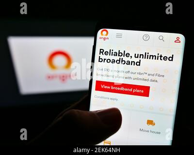 Persona che tiene il telefono mobile con il Web site del fornitore di energia australiano Origin Energy Ltd sullo schermo davanti al logo dell'azienda. Mettere a fuoco il display del telefono. Foto Stock