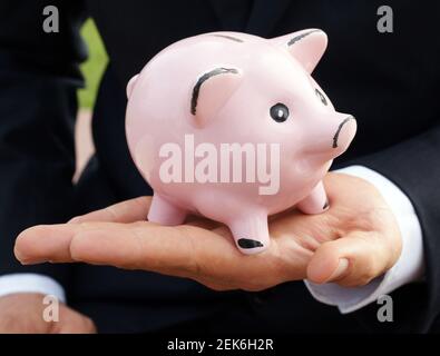 L'uomo d'affari alimenta la banca dei piggy con la banconota tedesca - risparmio di concetto fondi di prestito che investono denaro Foto Stock