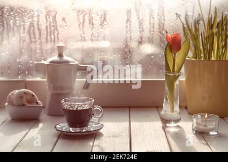 Caffè orientale in tradizionale caffettiera turca di rame con fiori sul davanzale della finestra. Davanzale in legno con tulipani arancioni e vaso di fiori di giacinto Foto Stock