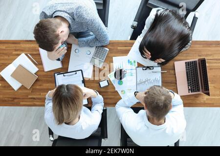 Gruppo di persone che siedono a tavola e tengono la testa vista dall'alto Foto Stock