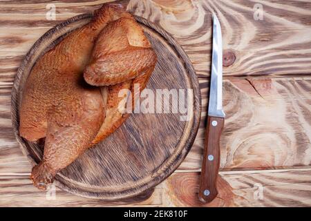 mezzo pollo grigliato su tavola di legno con coltello affilato. pollo fritto su tavola di legno con spazio copia. carne arrosto. Foto Stock