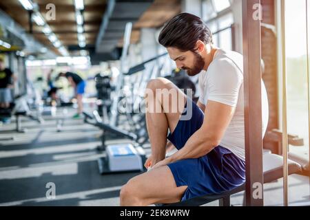 Immagine di forte bell'uomo che lega le sue scarpe in palestra prima di allenarsi. Foto Stock
