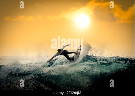 Giovane surfista con muta godendo grandi onde a Tenerife, Isole Canarie. Ragazzo sportivo che cavalcava la sua tavola da surf sull'onda dell'oceano. Coraggioso adolescente maki Foto Stock