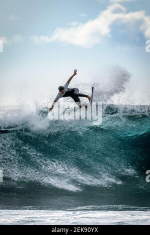 Giovane surfista con muta godendo grandi onde a Tenerife, Isole Canarie. Ragazzo sportivo che cavalcava la sua tavola da surf sull'onda dell'oceano. Coraggioso adolescente maki Foto Stock