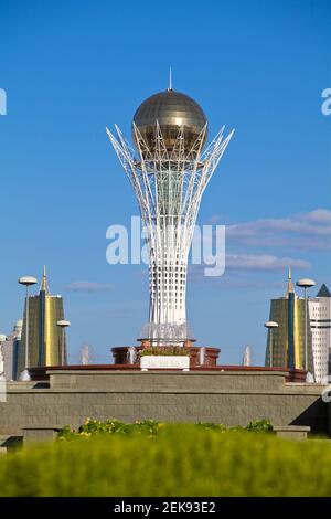 Kazakhstan, Astana, Nurzhol Bulvar - viale centrale, aiuole che conducono alla Torre Bayterek, fiancheggiate da due centri d'affari conici dorati Foto Stock