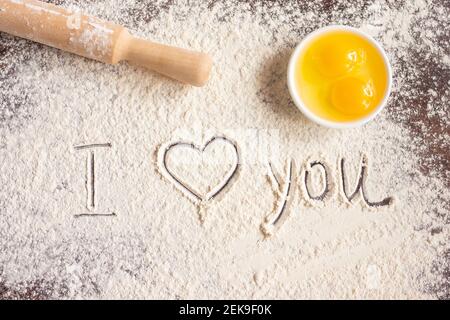 L'iscrizione ti amo su farina spruzzata, spilla e uova. Ricette di cottura. Concetto di San Valentino. Dichiarazione d'amore Foto Stock