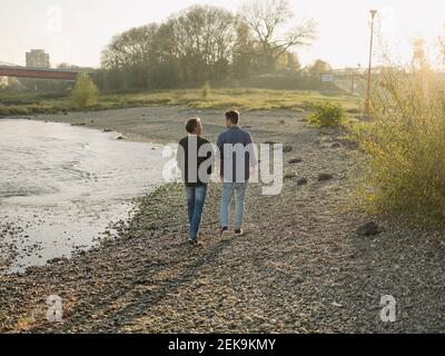 Padre e figlio camminano in riva al fiume in autunno Foto Stock