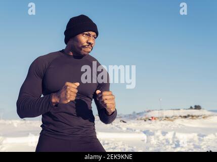 Atleta che guarda via mentre si è in piedi nella neve contro il cielo Foto Stock