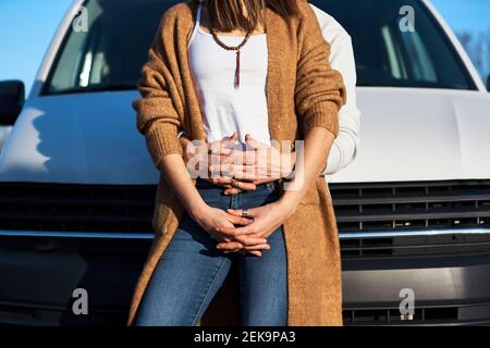 Fidanzato abbracciando la ragazza da dietro mentre si appoggia sulla macchina Foto Stock